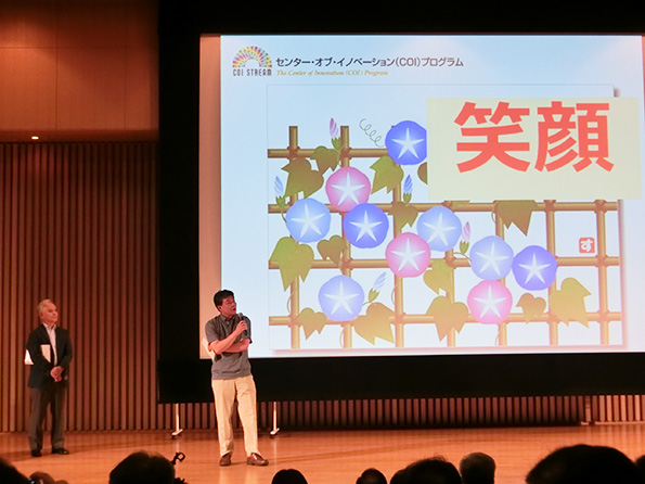 「名古屋COI拠点　オープンデイ2014」で挨拶する、文部科学省　科学技術・学術政策局　産業連携・地域支援課長の木村直人氏。となりは、名古屋大学総長の濱口道成氏。