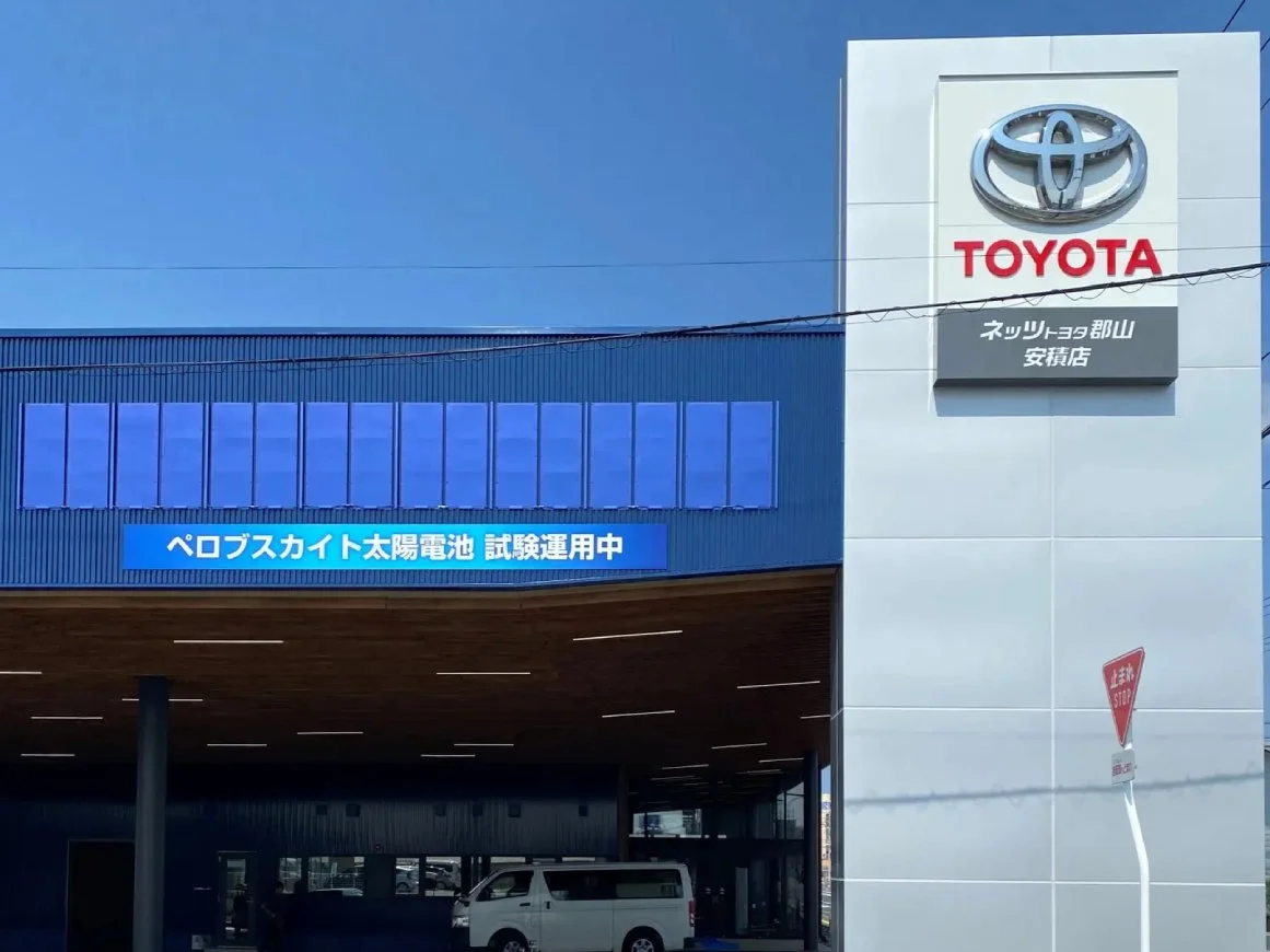 ネッツトヨタ郡山安積店の壁面に設置されたペロブスカイト太陽電池。店舗カラーの青色に可飾して実証する（出所：アイシン）